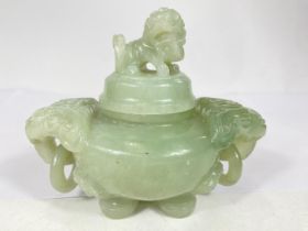 A Chinese jade coloured hardstone censor with hoop handles, mythical beast carved finial and side