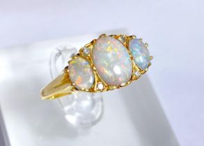 An 18 carat gold dress ring set large central opal flanked by 2 smaller opals and 4 small diamonds