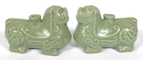 A pair of Chinese celadon glaze candleholders in the form of Shi Shi, 13cm length