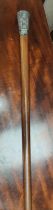 A Chinese military style walking cane with white metal embossed final with plants etc