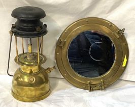 A vintage hanging port hole mirror and a brass vintage lamp.