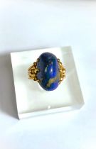 A yellow metal dress ring set yellow seamed lapis lazuli coloured stone, Egyptian marks to shank,