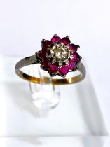 A yellow metal ring stamped 18ct with central illusion set diamond surrounded by rubies, 4.2gm