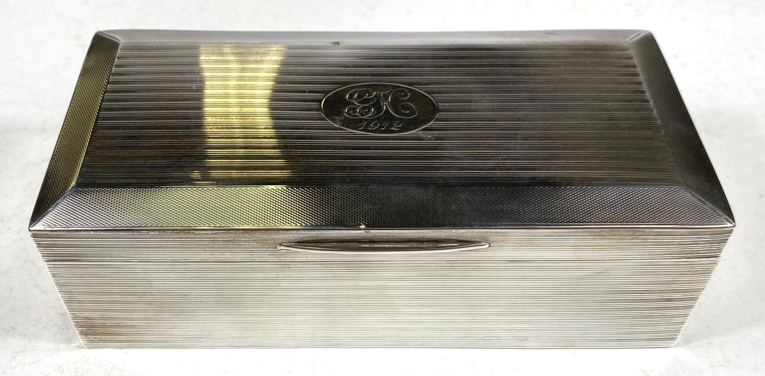 A hallmarked silver cigarette box, engine turned, on weighted base, Birmingham 1911