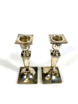 A hallmarked silver pair of candlesticks with square tapering columns on square weighted bases,