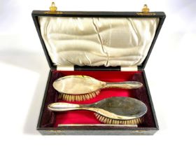 A silver pair of cased hairbrushes and a comb