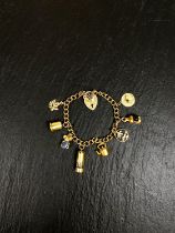 A yellow metal charm bracelet, stamped 375, with heart lock and 7 charms (4 unmarked), gross