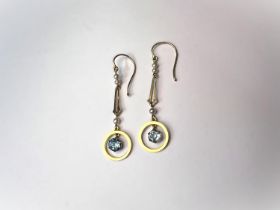 A pair of vintage yellow metal drop earrings with blue topaz hanging in a circle with seed pearls to