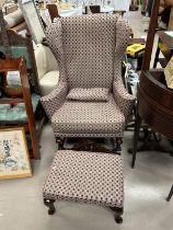 A mid 20th century wing back armchair and footstool in the Georgian style, re-upholstered in pink/