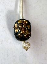 A Japanese metal bead decorated in bronze and gilt of a daemon, signed