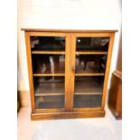 An early 20th century mahogany cabinet enclosed by 2 glazed doors