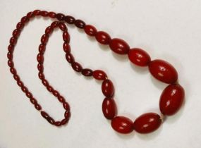 A string of cherry amber bakelite graduating beads, total length 79cm, smallest bead 1cm, largest