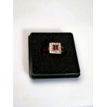 An 18ct gold Art Deco style dress ring set with ruby baguette cut stones surrounded by diamond