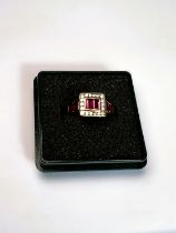 An 18ct gold Art Deco style dress ring set with ruby baguette cut stones surrounded by diamond