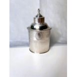 An oval white metal tea caddy with chased decoration, beaded rim and flared lower section marked for