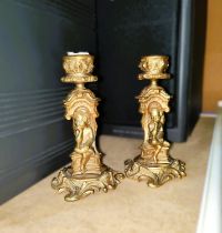 A pair of brass candlesticks in the Rococo manner with small children sitting on stem, 13cm ht