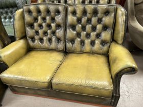 A pair of green leather effect Chesterfield style two seater settees, deep button back with