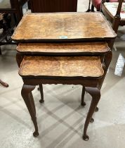 A burr walnut nest of three occasional tables with rectangular dish tops and a pair of pedestal wine