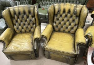 A pair of green leather effect Chesterfield style reclining armchairs, deep button back with studded