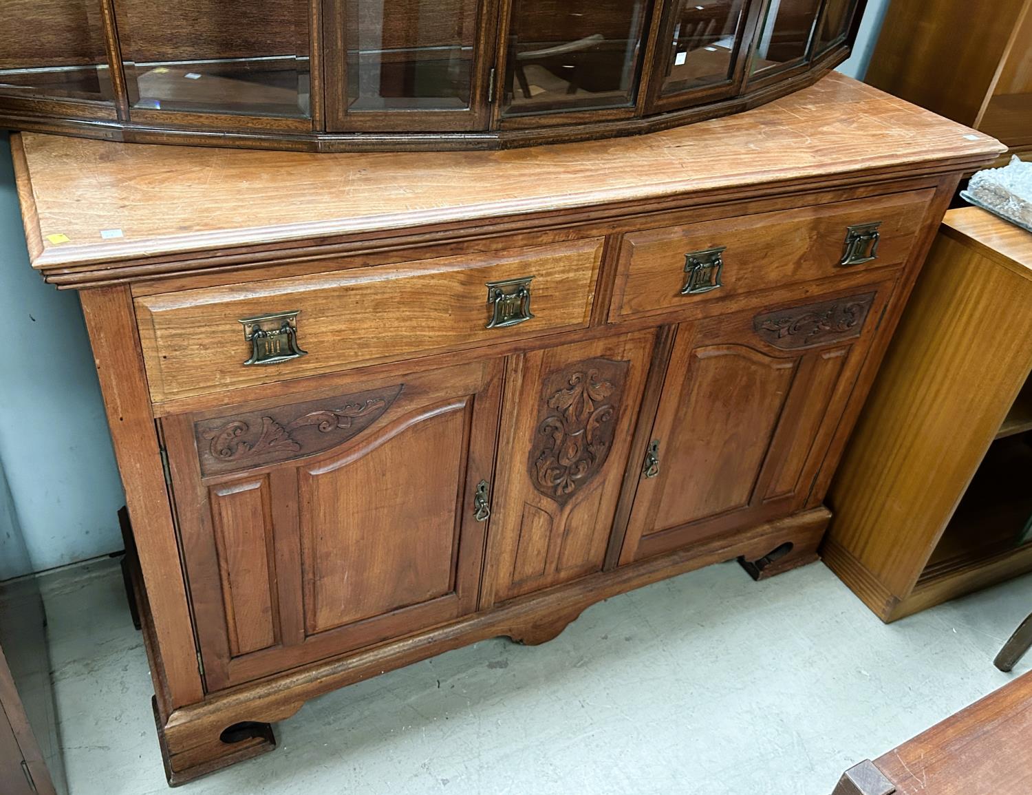 An Edwardian carved walnut sideboard base of two drawers and two cupboards on plinth.