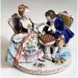 A Dresden style porcelain group:  man and woman in 18th century dress playing chess