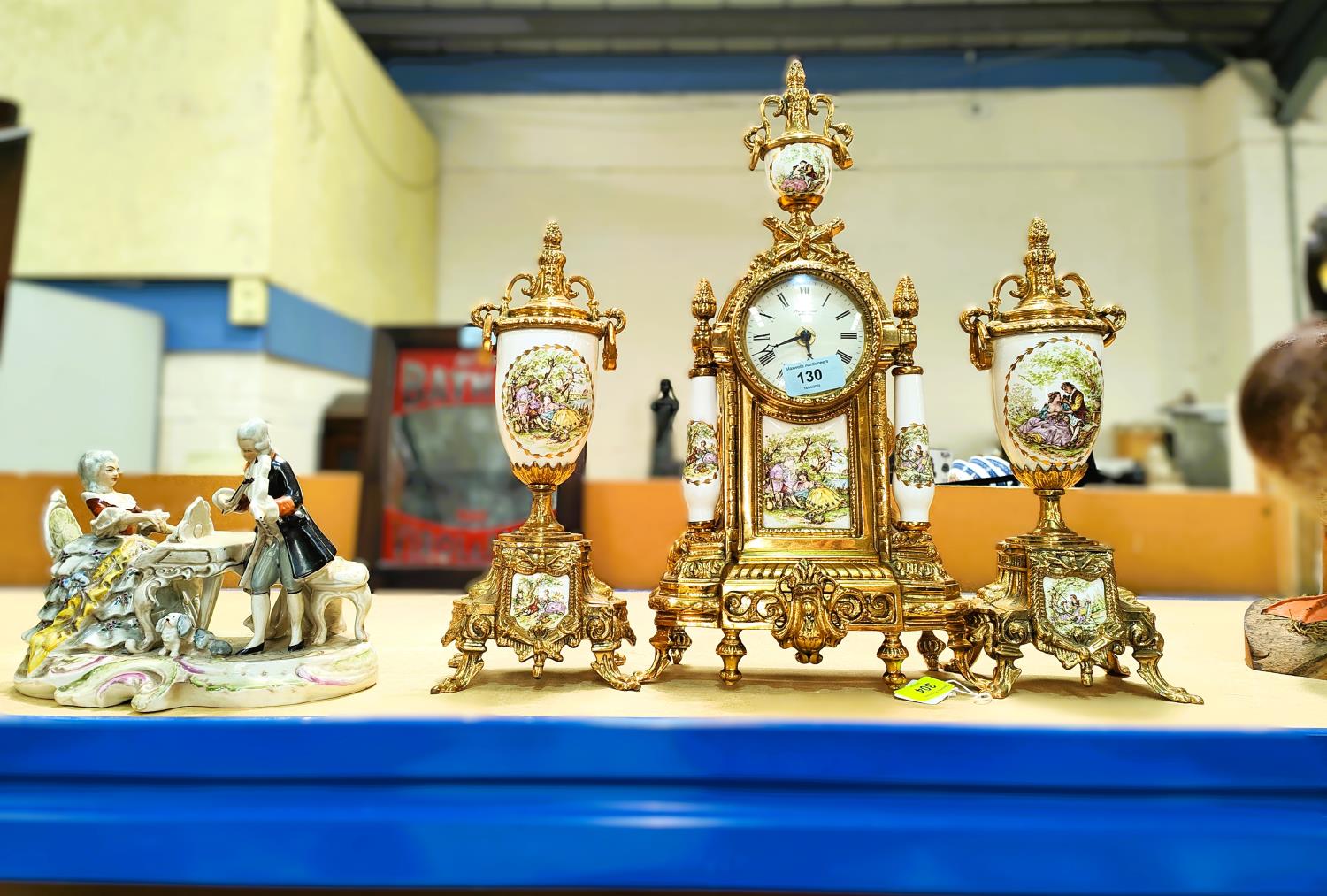 A traditional ceramic and metal three piece clock garniture with quartz movement, a Dresden style