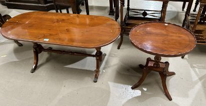 A reproduction yew wood coffee table with rounded rectangular top and twin pedestals on splay