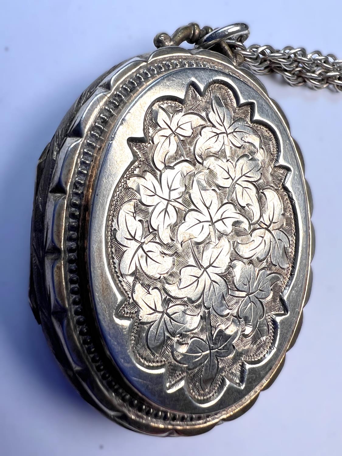 An oval chased white metal locket on later 'Prince of Wales' silver chain, length of chain 74cm - Image 2 of 4