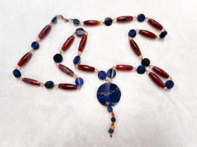 A long necklace formed from carnelian beads interspersed with circular flat lapis lazuli, clear