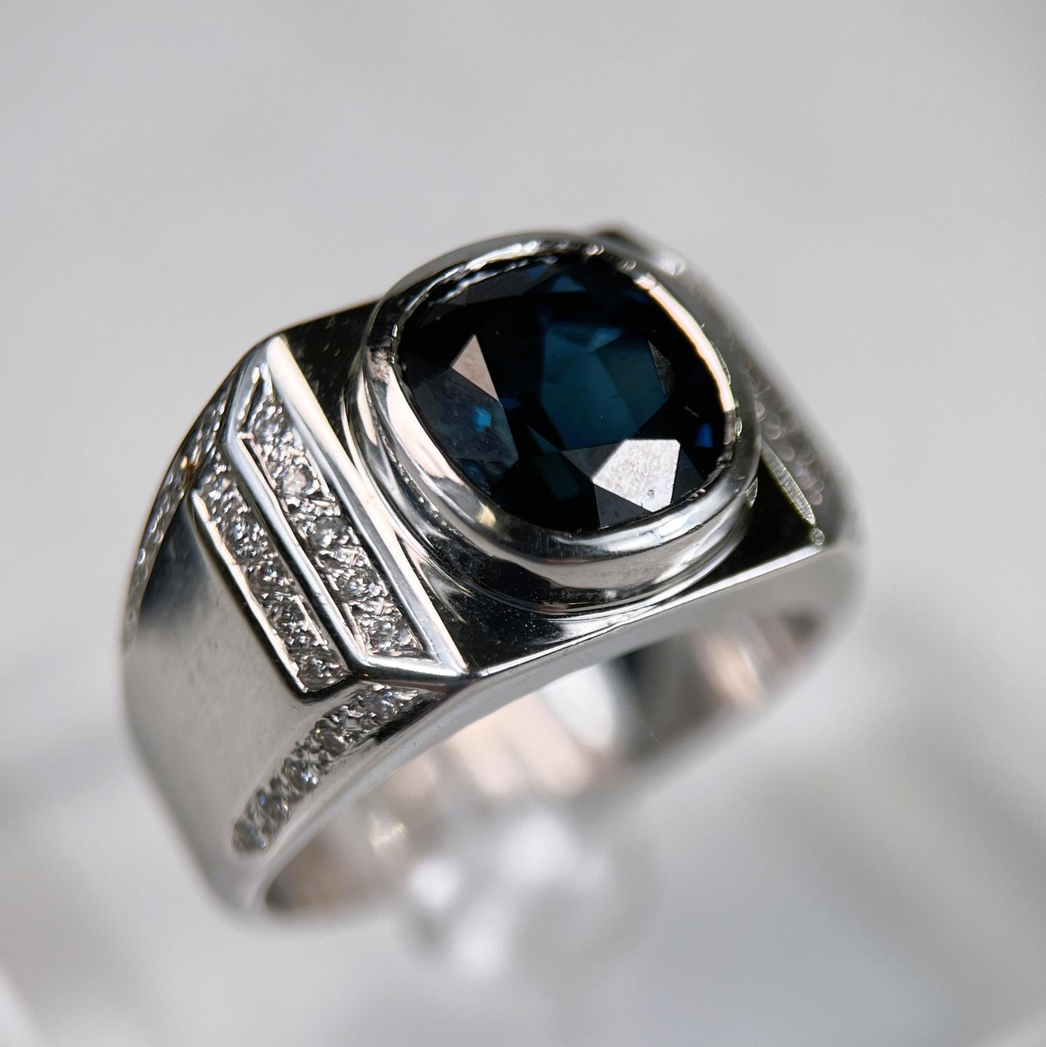 A gent's heavy dress ring with wide white metal shank set central cushion cut sapphire (10.5 x 9.