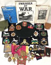A collection of interesting military cloth shoulder and other badges, metal military badges, beret