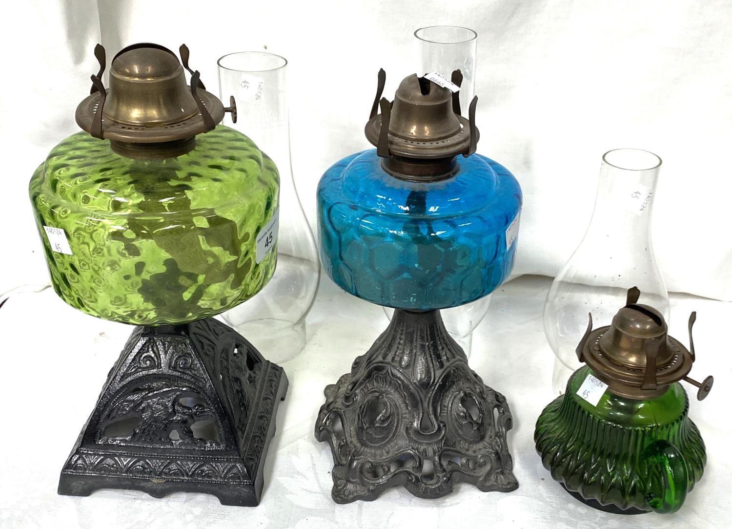 Two Victorian cast iron and coloured glass oil lamps and a smaller lamp