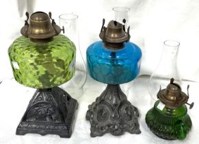 Two Victorian cast iron and coloured glass oil lamps and a smaller lamp