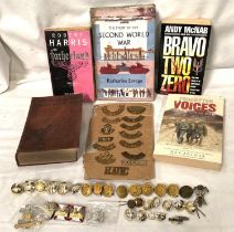 A collection of military shoulder badges on board, a collection of buttons etc and books including