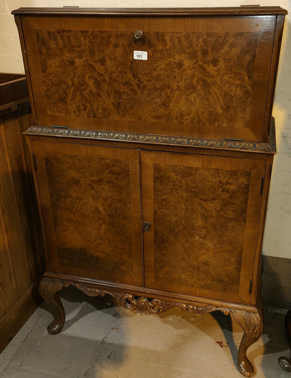 A reproduction Queen Anne style burr walnut drinks cabinet with fall front double cupboard and