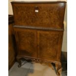 A reproduction Queen Anne style burr walnut drinks cabinet with fall front double cupboard and