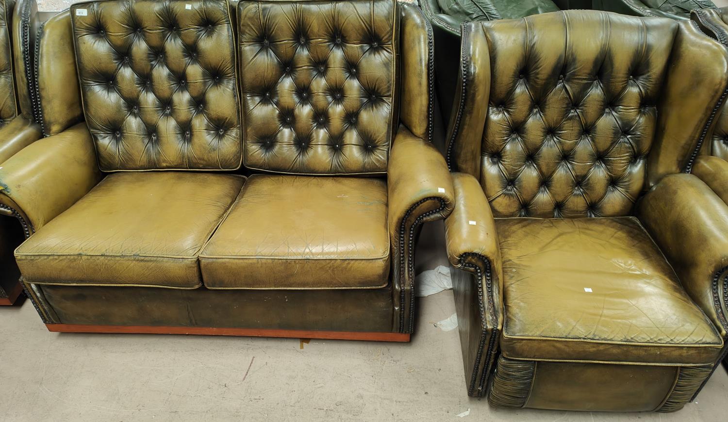 A green leather effect Chesterfield style reclining armchair with deep button back with studded