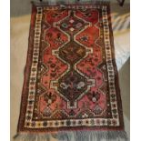 A 20th century hand knotted red ground Persian rug with central barred triple medallions