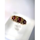 An 18 carat hallmarked gold ring set with 3 garnets and diamond chips, 5.5 gm, size L