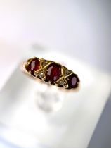 An 18 carat hallmarked gold ring set with 3 garnets and diamond chips, 5.5 gm, size L