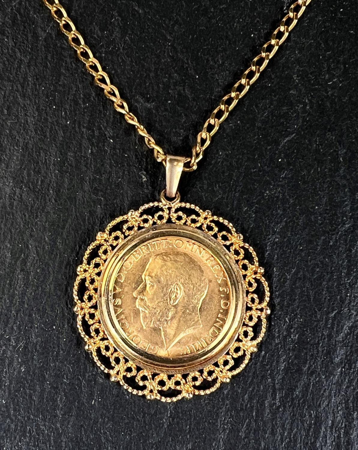 A George V sovereign in filigree pendant mount, on flattened curb chain, gross 18gm