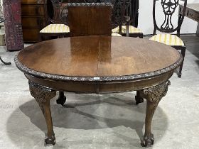 An early 20th century mahogany oval dining table, extending to 70" long with one extra leaf;