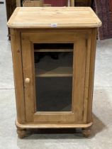 A pine cabinet enclosed by a glazed door with hinged top. 24" wide