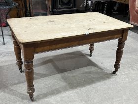 A Victorian pine kitchen table with scrubbed top on turned legs with ceramic castors. 56" long x 32"