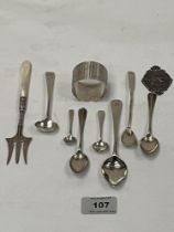 A collection of silver sppons; napkin ring; a silver pickle fork; a white metal St. Christopher