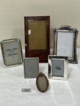 A silver photograph frame, four plated frames and a treen example.