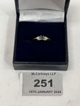 A 9ct three stone emerald and diamond ring. 1.3g gross. Size K.