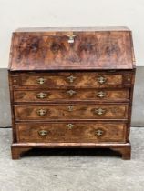 A George II walnut bureau, the crossbanded and herringbone banded fall over four long graduated