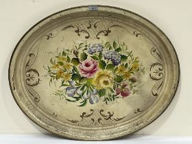 A tole oval serving tray painted with flowers in scrolled border. 28½" wide.