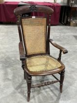 A Victorian stained beechwood armchair with caned back and seat, on turned legs.